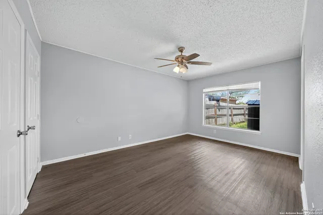 a view of an empty room with a window and wooden floor