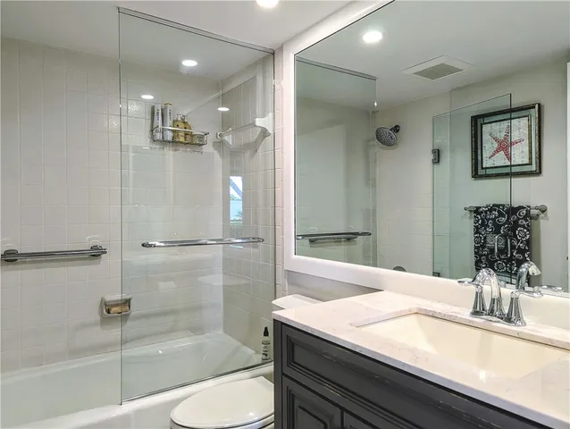 a bathroom with a granite countertop sink a toilet and shower