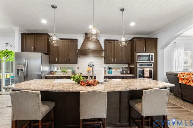 a kitchen with granite countertop a table chairs a sink dishwasher refrigerator and cabinets