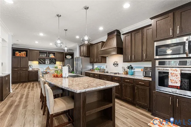 a kitchen with stainless steel appliances granite countertop a stove top oven a sink dishwasher a dining table and chairs with wooden floor