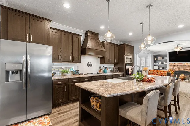a kitchen with granite countertop a table chairs stainless steel appliances and wooden floor