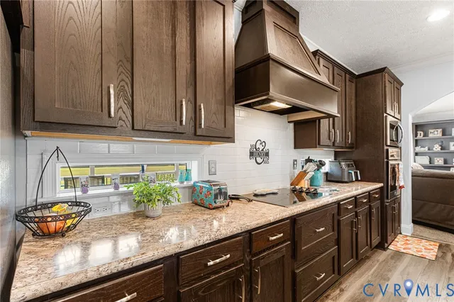 a kitchen with stainless steel appliances granite countertop a sink a stove and wooden cabinets