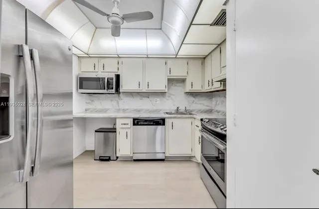 a kitchen with kitchen island granite countertop a sink cabinets and stainless steel appliances