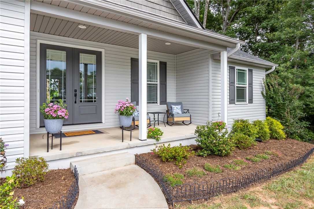 3080 McGee Road Iva, SC 29655 - Photo 3 of 49 A welcoming front porch features dual entry doors, inviting visitors to a cozy sitting area.