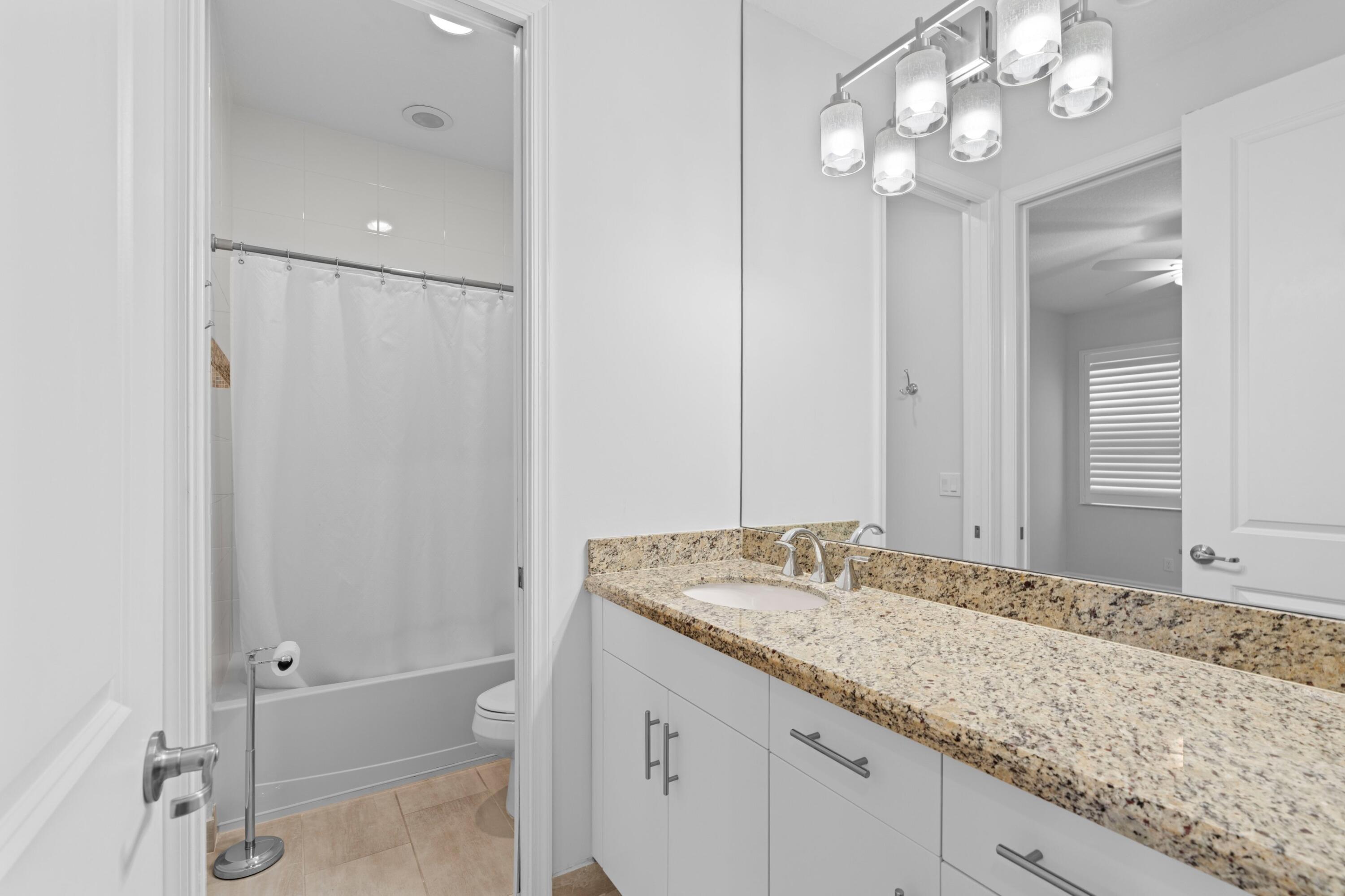 6693 Quiet Wave Trail, Unit 41 Boca Raton, FL 33433 - Photo 15 of 40 a bathroom with a granite countertop sink a large mirror and a shower