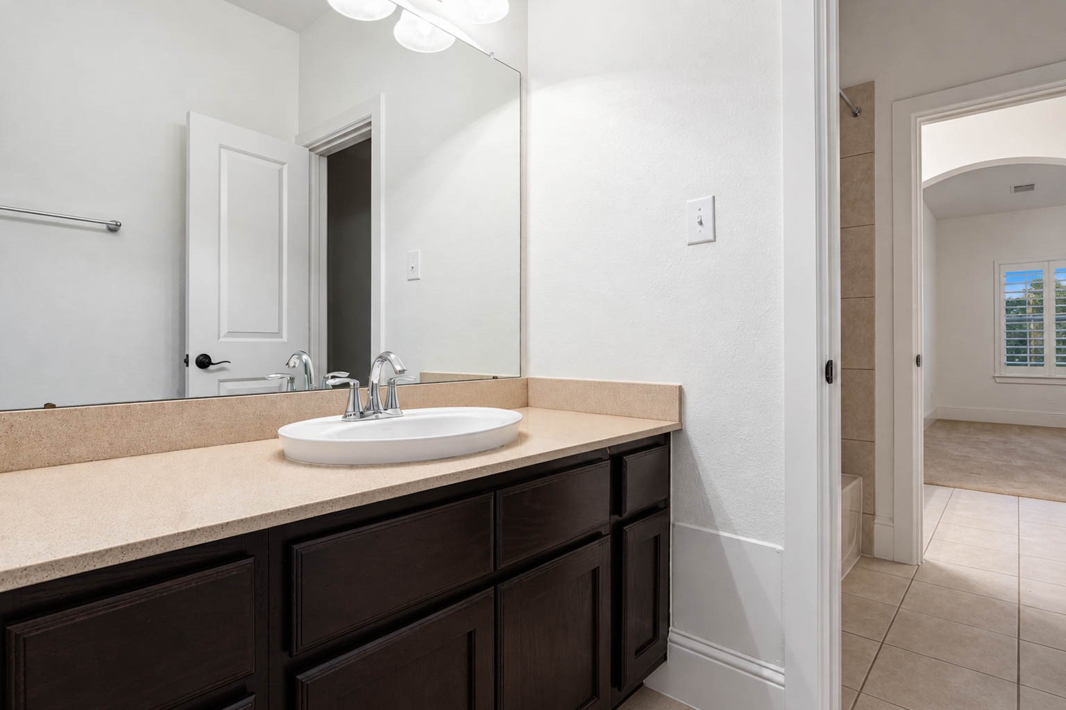 5403 Mesquite Ridge Street Fulshear, TX 77441 - Photo 32 of 42 This Hollywood bathroom connects the guest bedrooms and gives each side its own vanity, with dark cabinetry, a generous counter, and polished nickel fixtures. A tub and shower combination sits between the two vanities, keeping mornings simple for everyone.