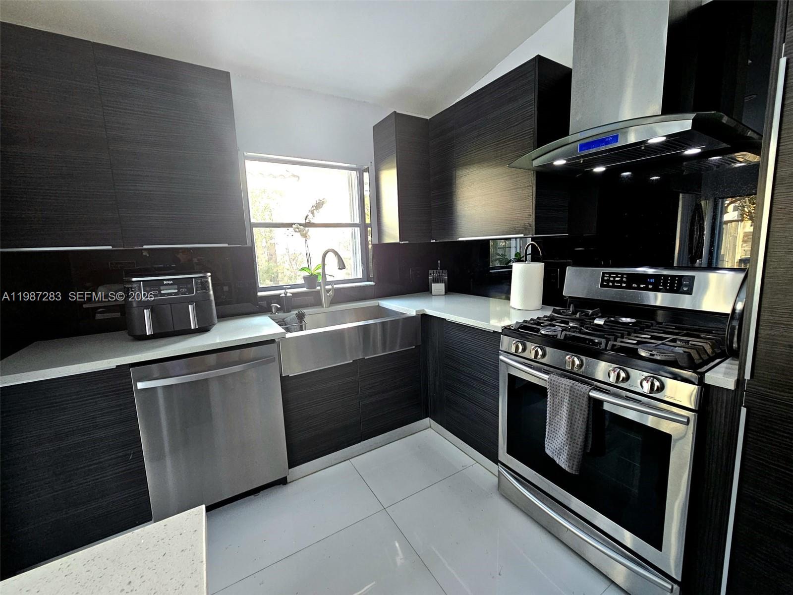 8003 Southwest 158th Place Miami, FL 33193 - Photo 7 of 20 a kitchen with stainless steel appliances a stove a sink and a microwave