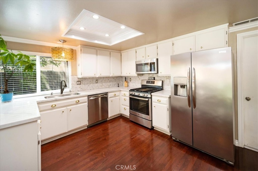 a kitchen with white cabinets stainless steel appliances and window