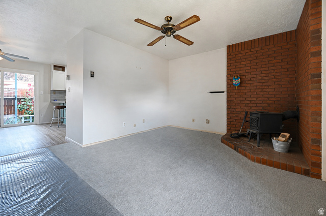 285 West 600 North, Unit 2 Logan, UT 84321 - Photo 4 of 21 Carpeted living space featuring a brick fireplace with a wood-burning stove and a ceiling fan