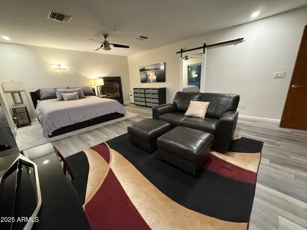 a bedroom with a bed couch and wooden floor