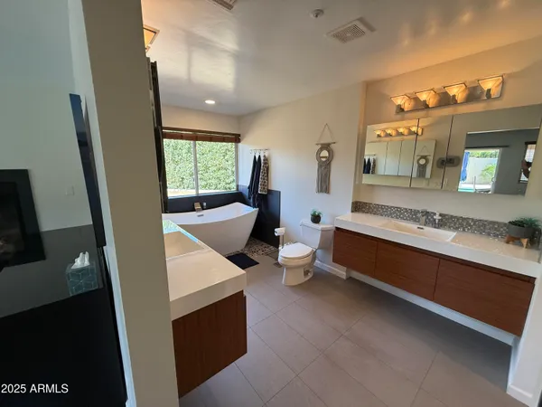 a spacious bathroom with a double vanity sink a mirror and a bathtub