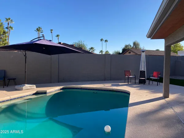 a view of a backyard with table and chairs under an umbrella