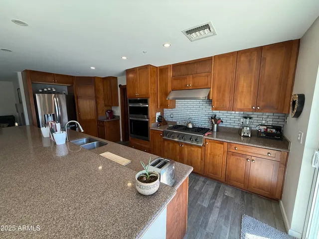 a kitchen with stainless steel appliances granite countertop a refrigerator sink and stove