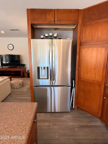 a kitchen with stainless steel appliances granite countertop a refrigerator a stove and a sink with wooden floors