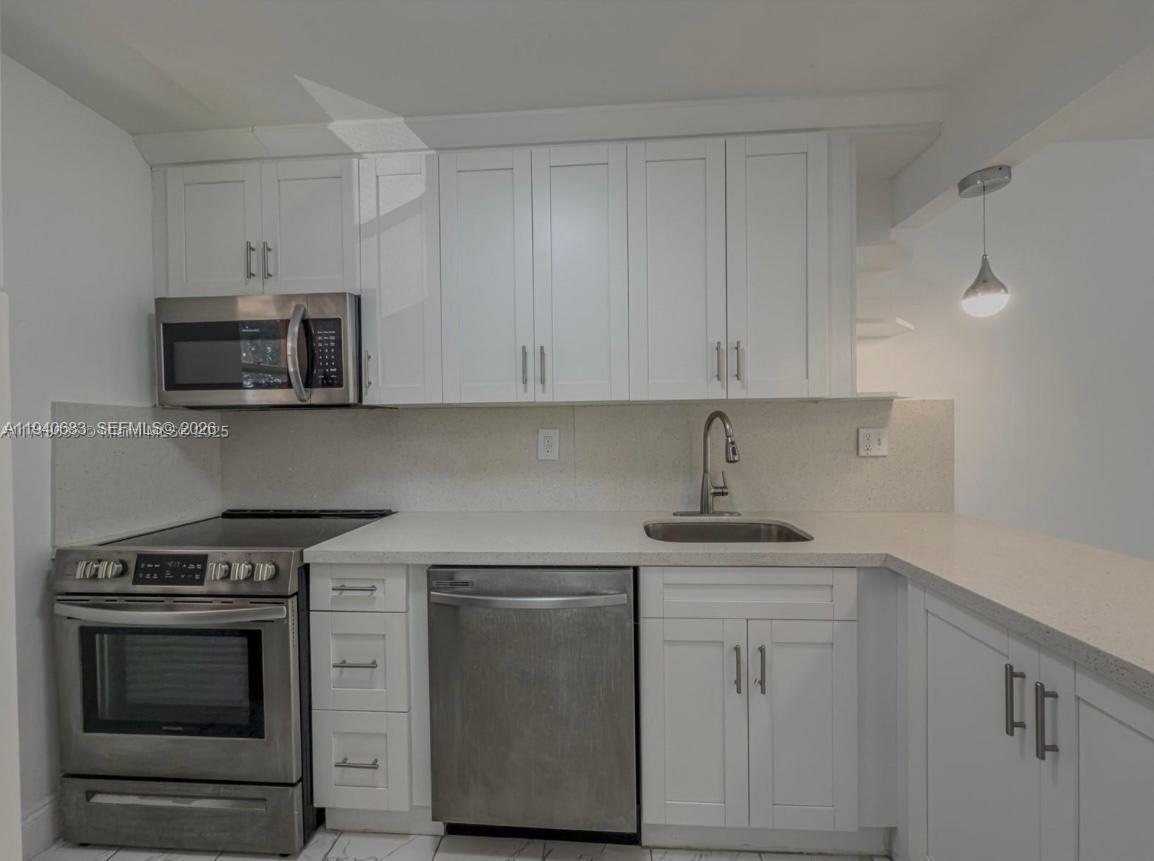 7610 Stirling Road, Unit 207F Davie, FL 33024 - Photo 4 of 22 a kitchen with white cabinets and stainless steel appliances