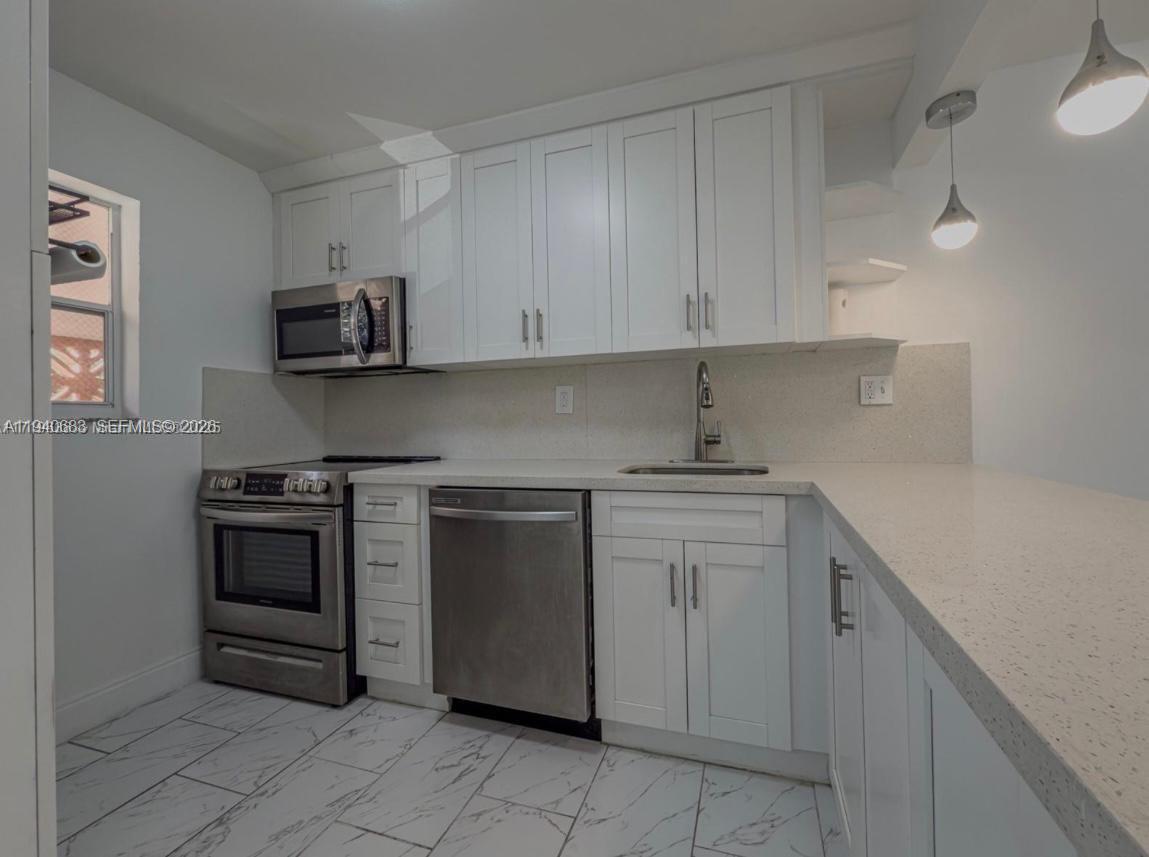7610 Stirling Road, Unit 207F Davie, FL 33024 - Photo 5 of 22 a kitchen with white cabinets and stainless steel appliances
