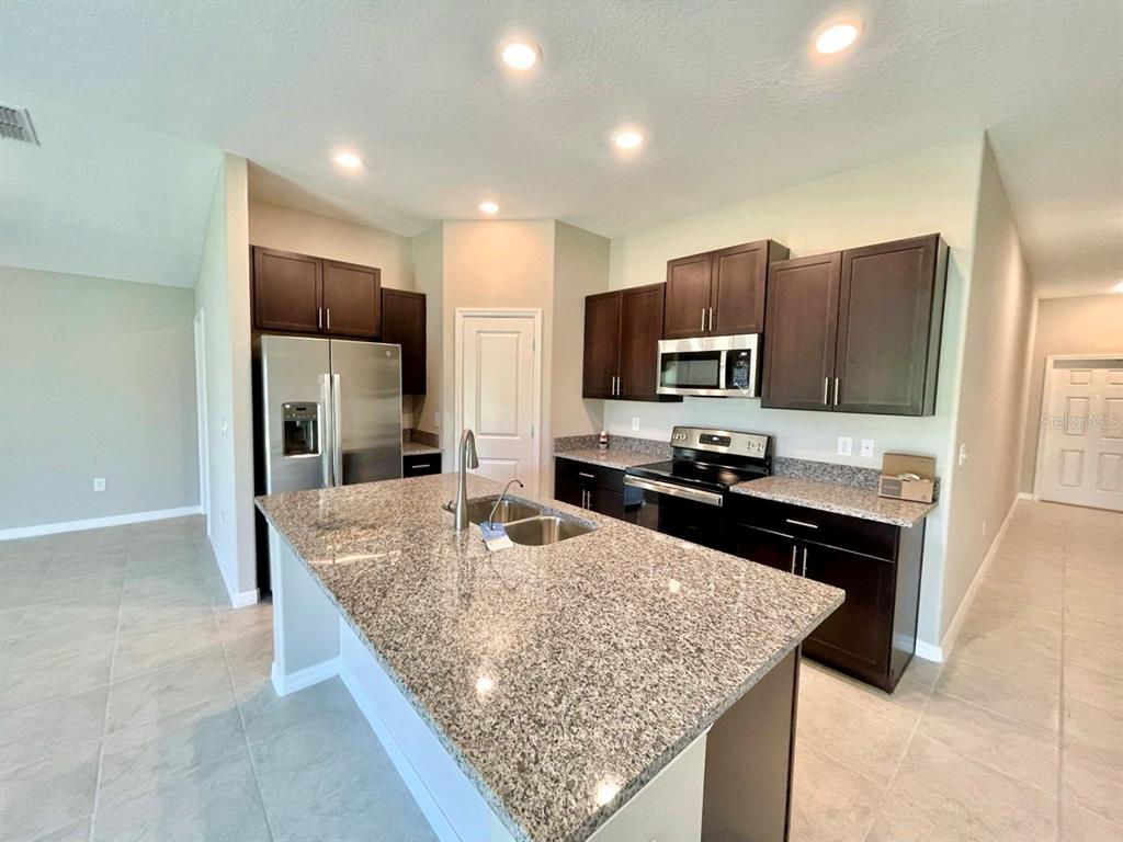 869 Anchor Bend Drive Ruskin, FL 33570 - Photo 4 of 23 a kitchen with stainless steel appliances granite countertop a sink refrigerator and microwave