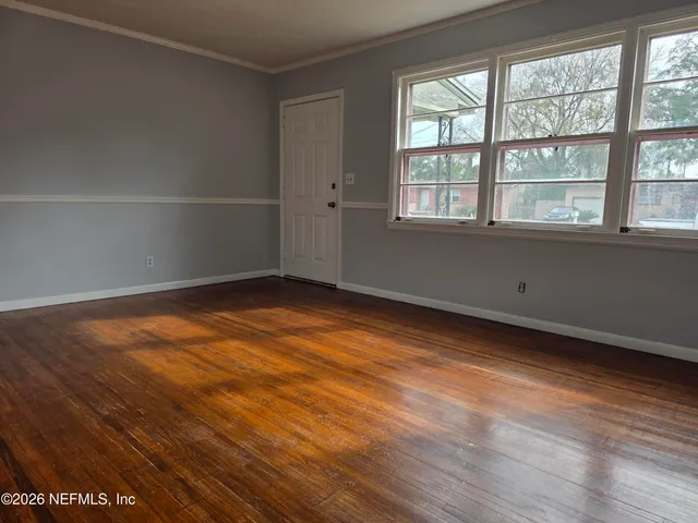an empty room with wooden floor and windows