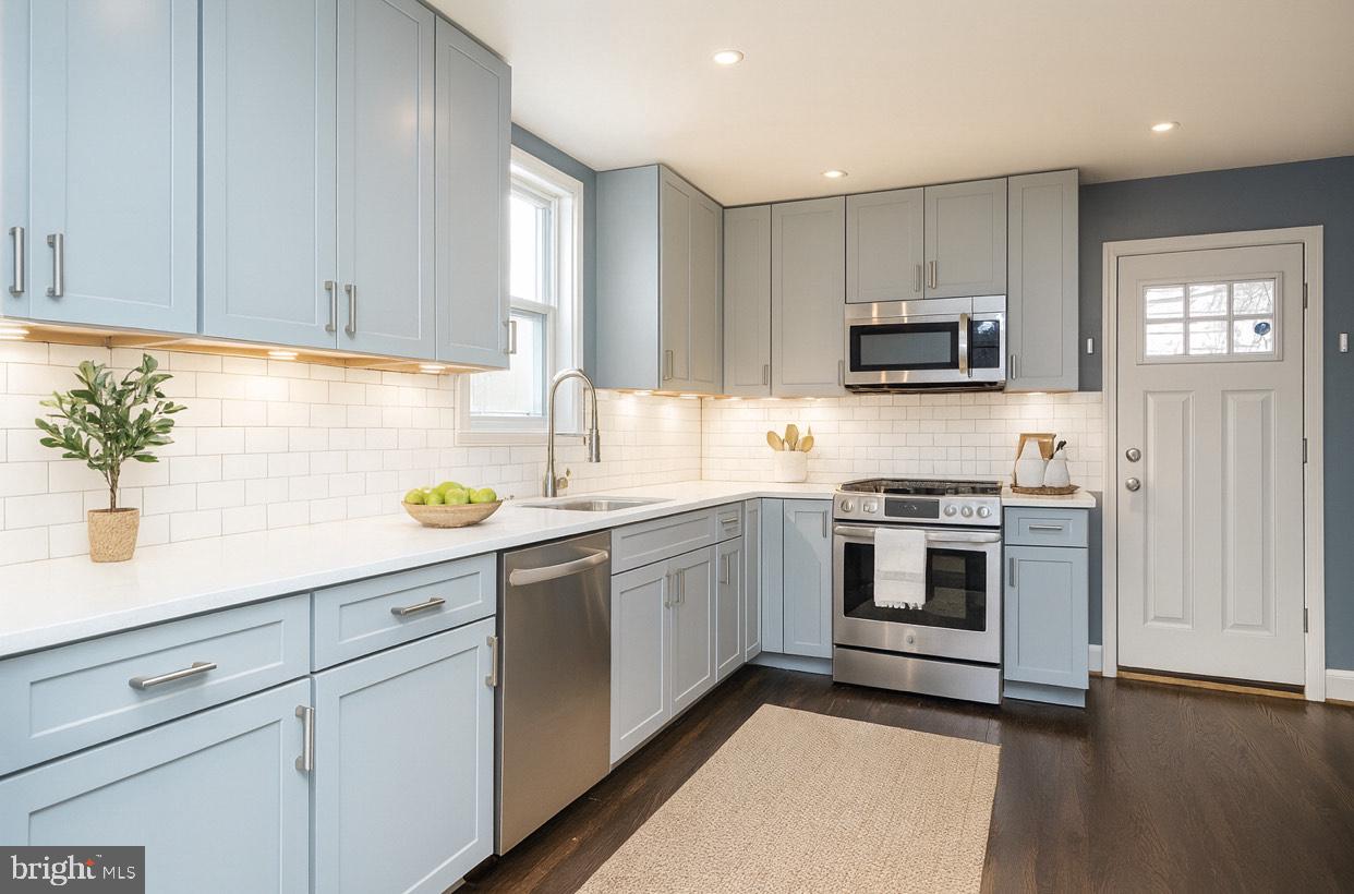 a kitchen with cabinets stainless steel appliances and wooden floor