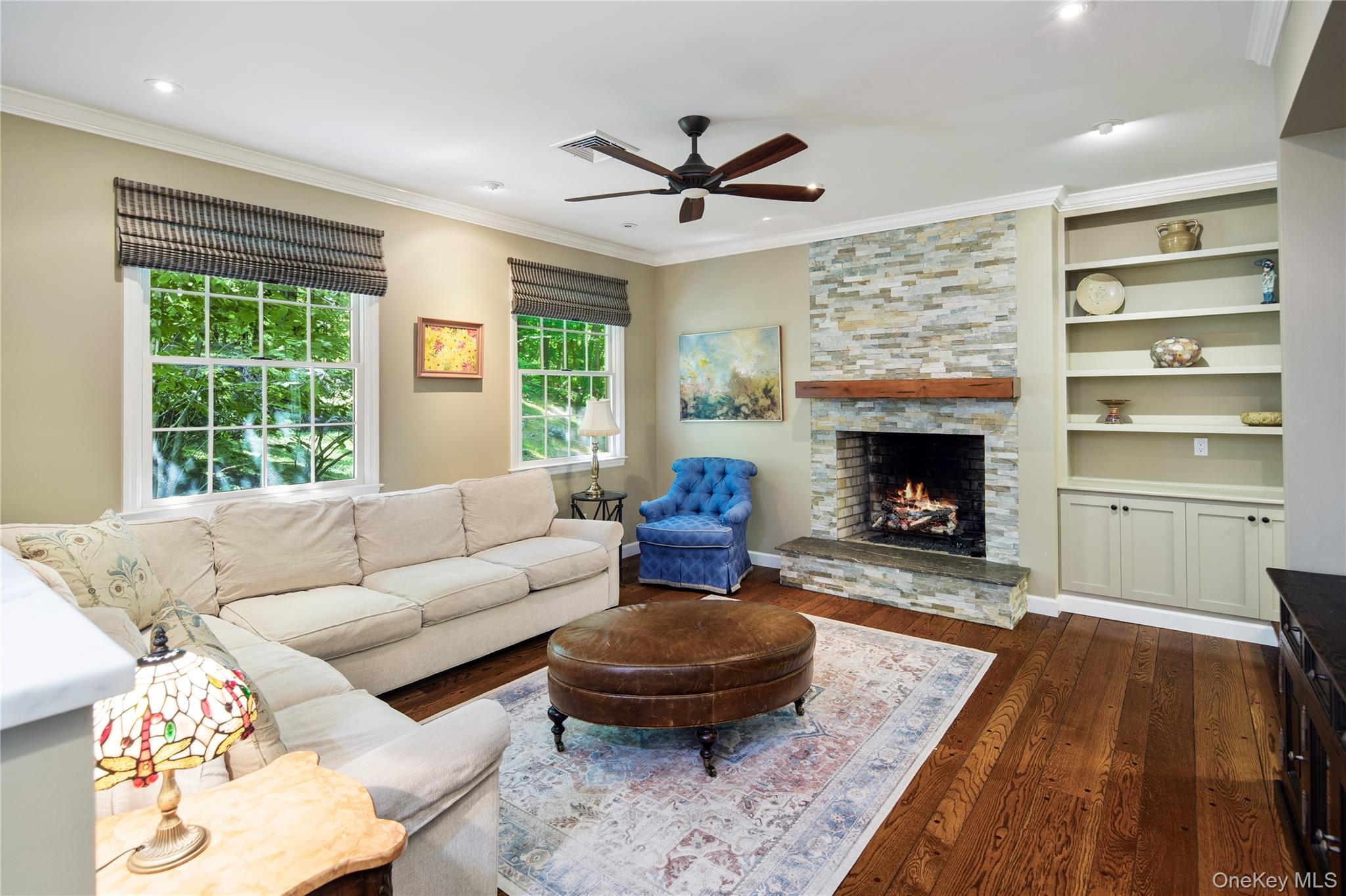 105 Cross Ridge Road Chappaqua, NY 10514 - Photo 11 of 43 The living room features a raised hearth fireplace with stacked stone floor to ceiling surround and thick wood mantle shelf, flanked by built-in cabinetry and shelving, recessed eyeball lighting, a ceiling fan, crown molding and refinished pegged wide board oak floors. Opens directly onto newly renovated eat-in kitchen and dining area.