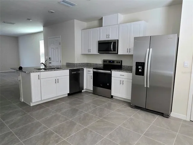 a kitchen with stainless steel appliances granite countertop a sink a stove a microwave a sink a counter top space and cabinets