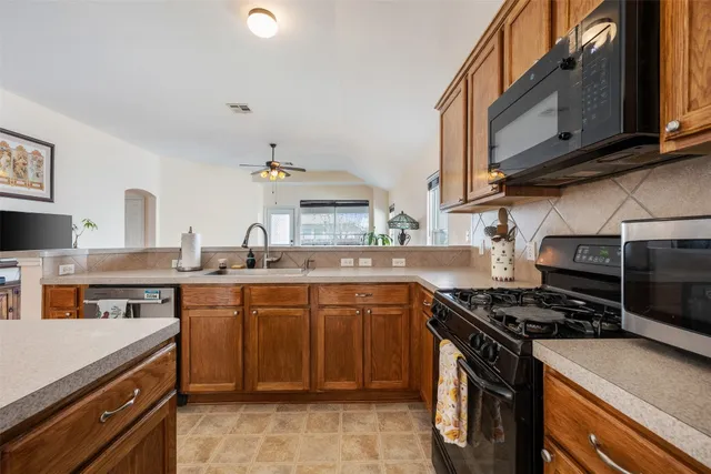 a kitchen with a stove a sink a refrigerator and wooden floor