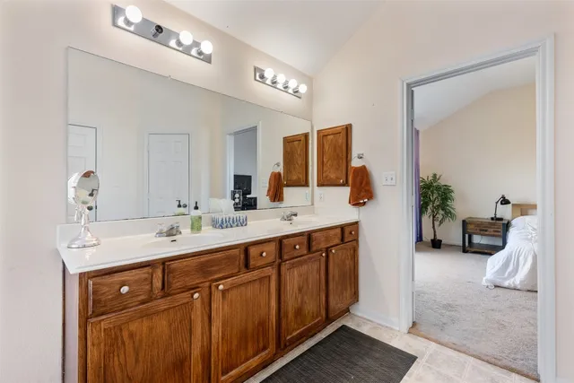 a spacious bathroom with a double vanity sink a large mirror and a bathtub