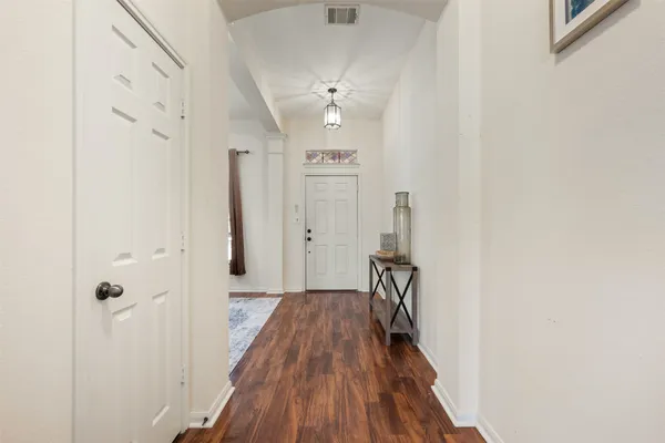 a view of a hallway with wooden floor and a bathroom