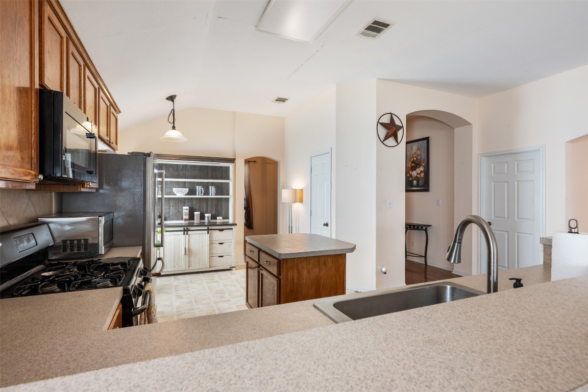 221 Stone Crest Boulevard Buda, TX 78610 - Photo 7 of 33 a kitchen with stainless steel appliances kitchen island granite countertop a refrigerator and a stove top oven