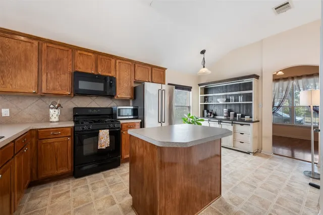 a kitchen with stainless steel appliances kitchen island granite countertop a refrigerator and a stove top oven