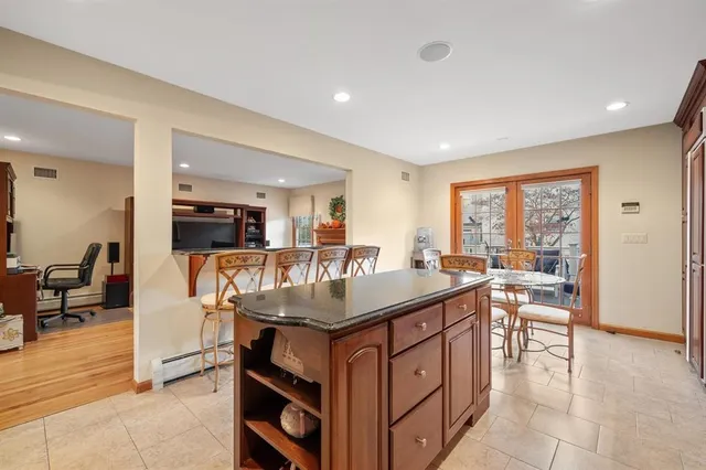 a kitchen with stainless steel appliances granite countertop a table chairs and a refrigerator
