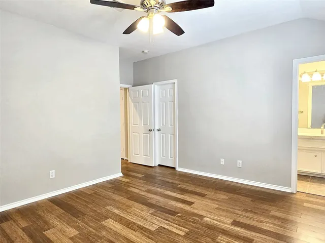an empty room with a ceiling fan and wooden floor
