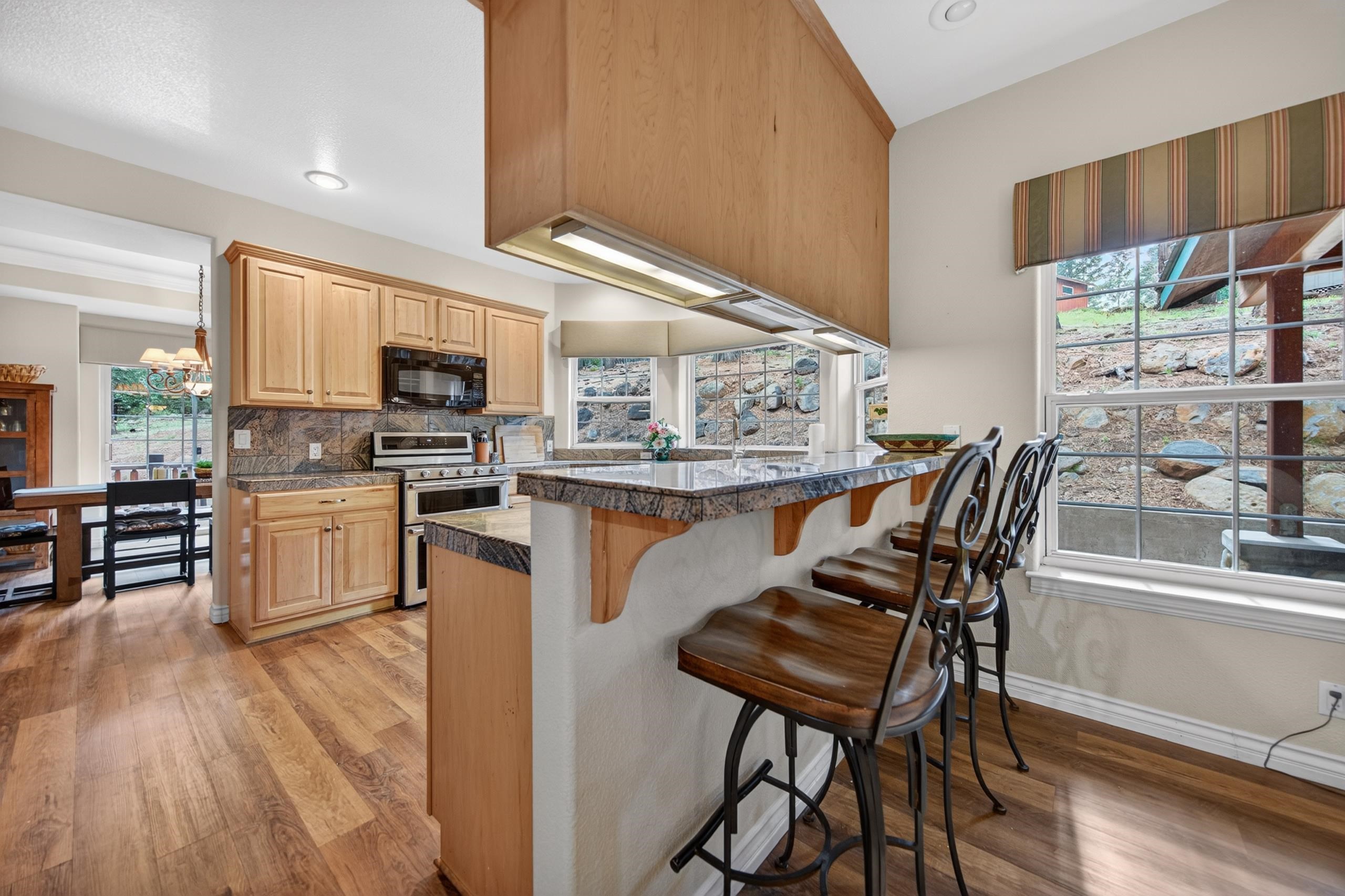 1017 Timber Ridge Road Lake Almanor, CA 96137 - Photo 14 of 45 a kitchen with stainless steel appliances kitchen island granite countertop a stove a refrigerator and a dining table with wooden floor