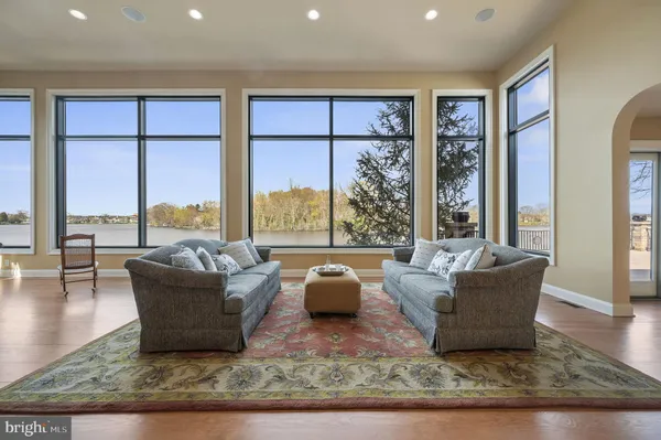 a living room with furniture large windows wooden floor and a rug