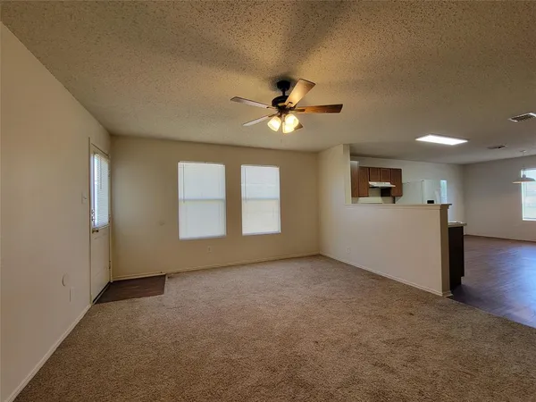 an empty room with windows and ceiling fan