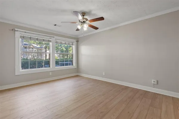 a view of an empty room with wooden floor and a window