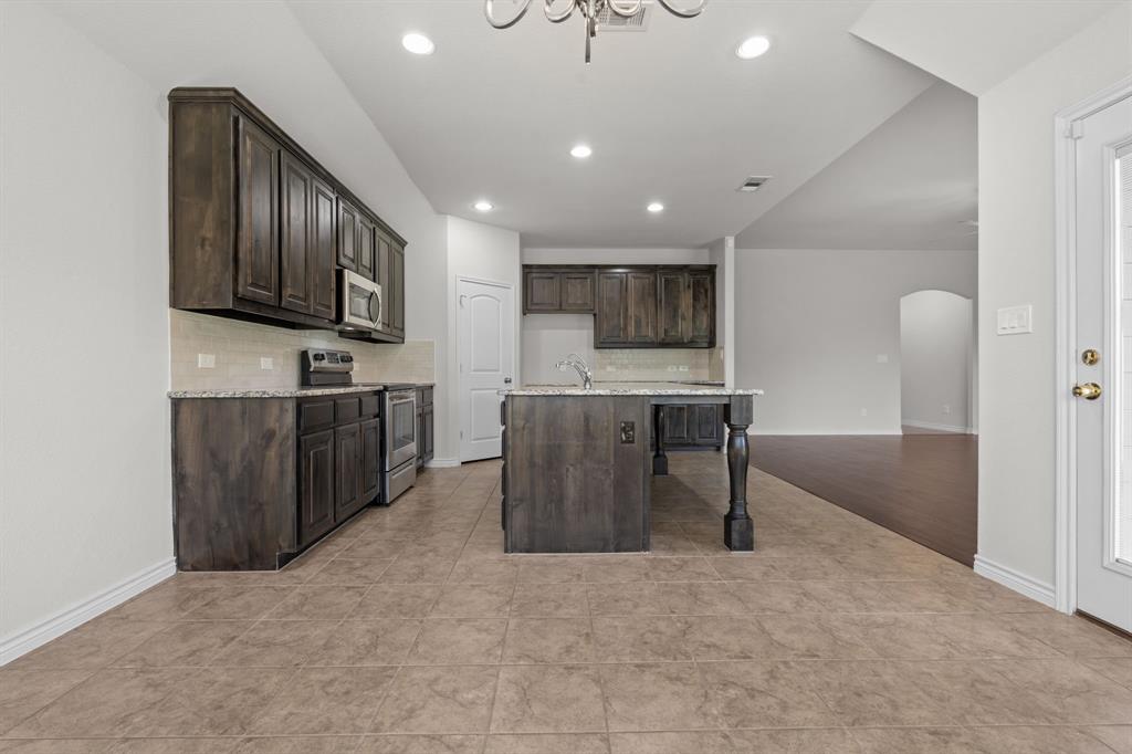 217 Angelina Court Azle, TX 76020 - Photo 9 of 34 a kitchen with kitchen island granite countertop a stove top oven a sink a dining table and chairs