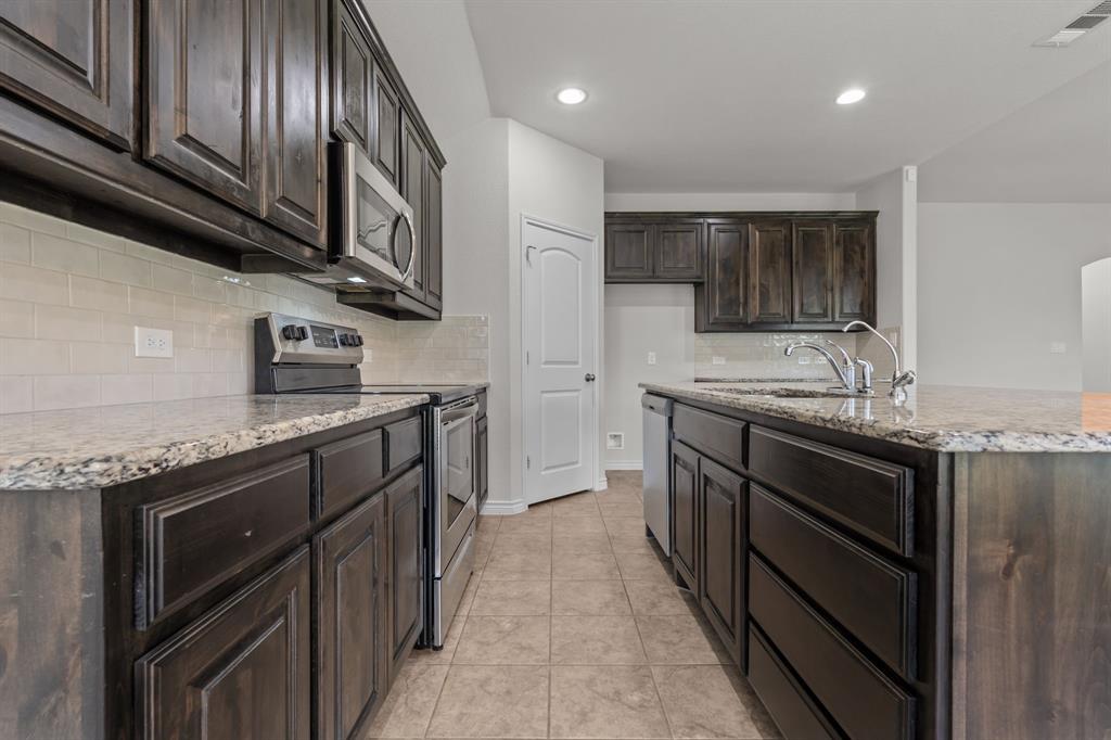 217 Angelina Court Azle, TX 76020 - Photo 10 of 34 a kitchen with stainless steel appliances granite countertop a large stove a sink dishwasher and a refrigerator