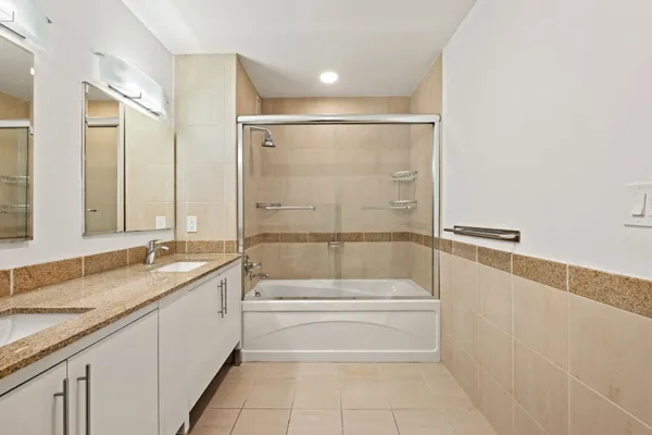 a bathroom with a granite countertop bathtub shower sink and mirror