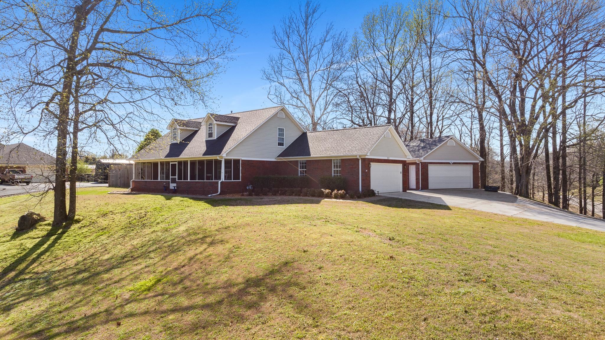 View of front of house with roof with shingles, a front yard, driveway, and a garage