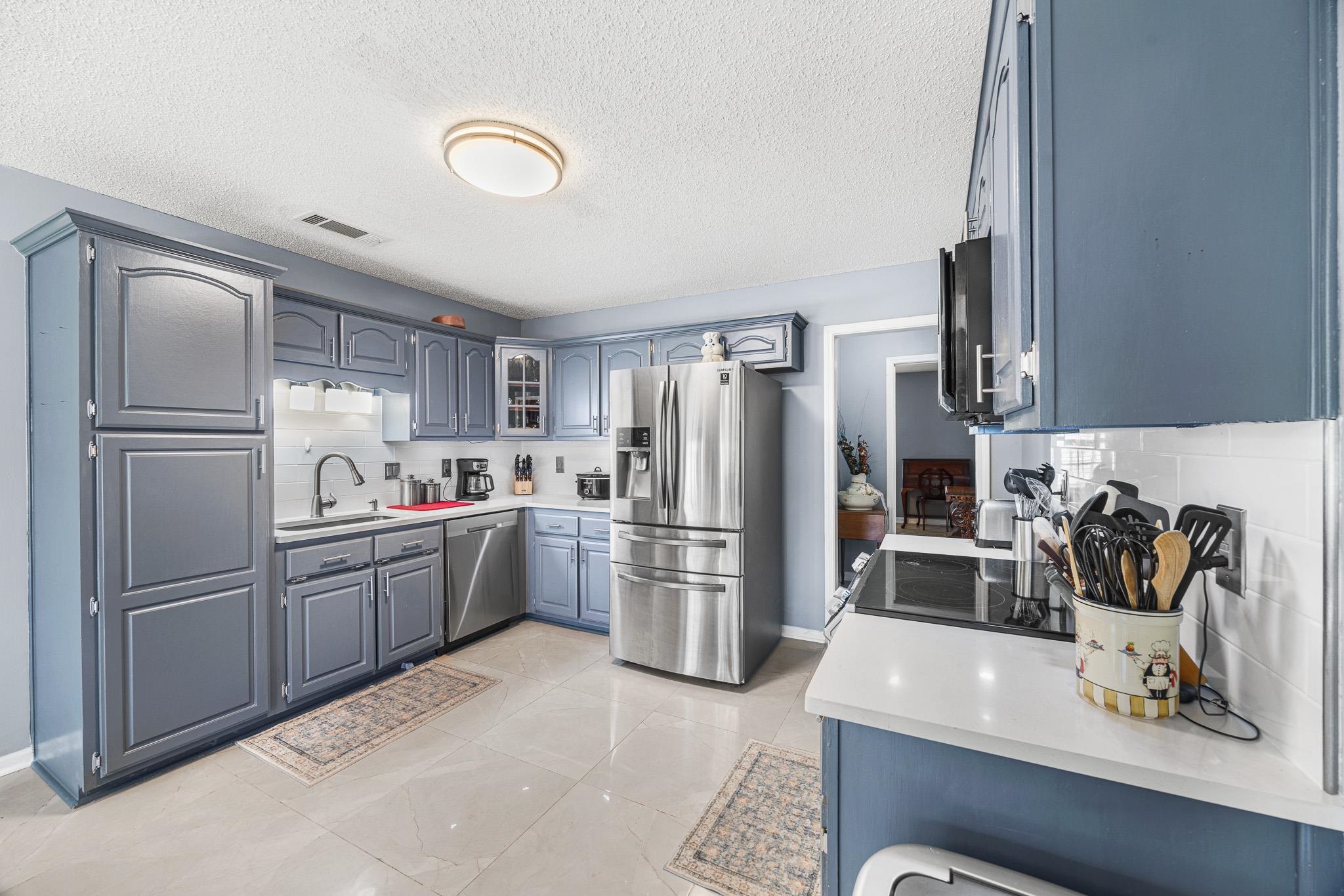 149 Abby Road Drummonds, TN 38023 - Photo 11 of 38 Kitchen with stainless steel appliances, decorative backsplash, light countertops, glass insert cabinets, and a textured ceiling
