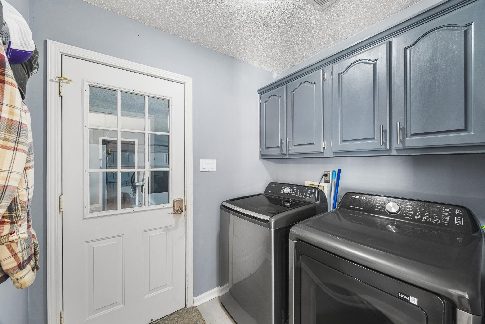 149 Abby Road Drummonds, TN 38023 - Photo 23 of 38 Laundry room featuring washer and clothes dryer, a textured ceiling, and cabinet space