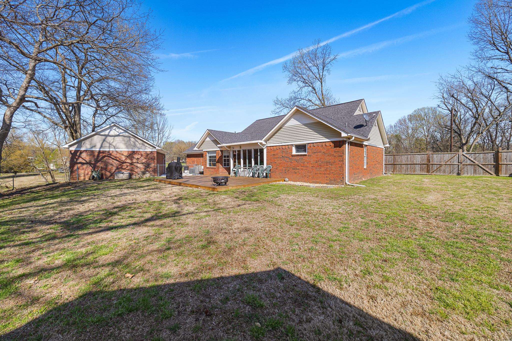 149 Abby Road Drummonds, TN 38023 - Photo 34 of 38 Rear view of house featuring a fenced backyard, an outdoor structure, a wooden deck, brick siding, and a shingled roof