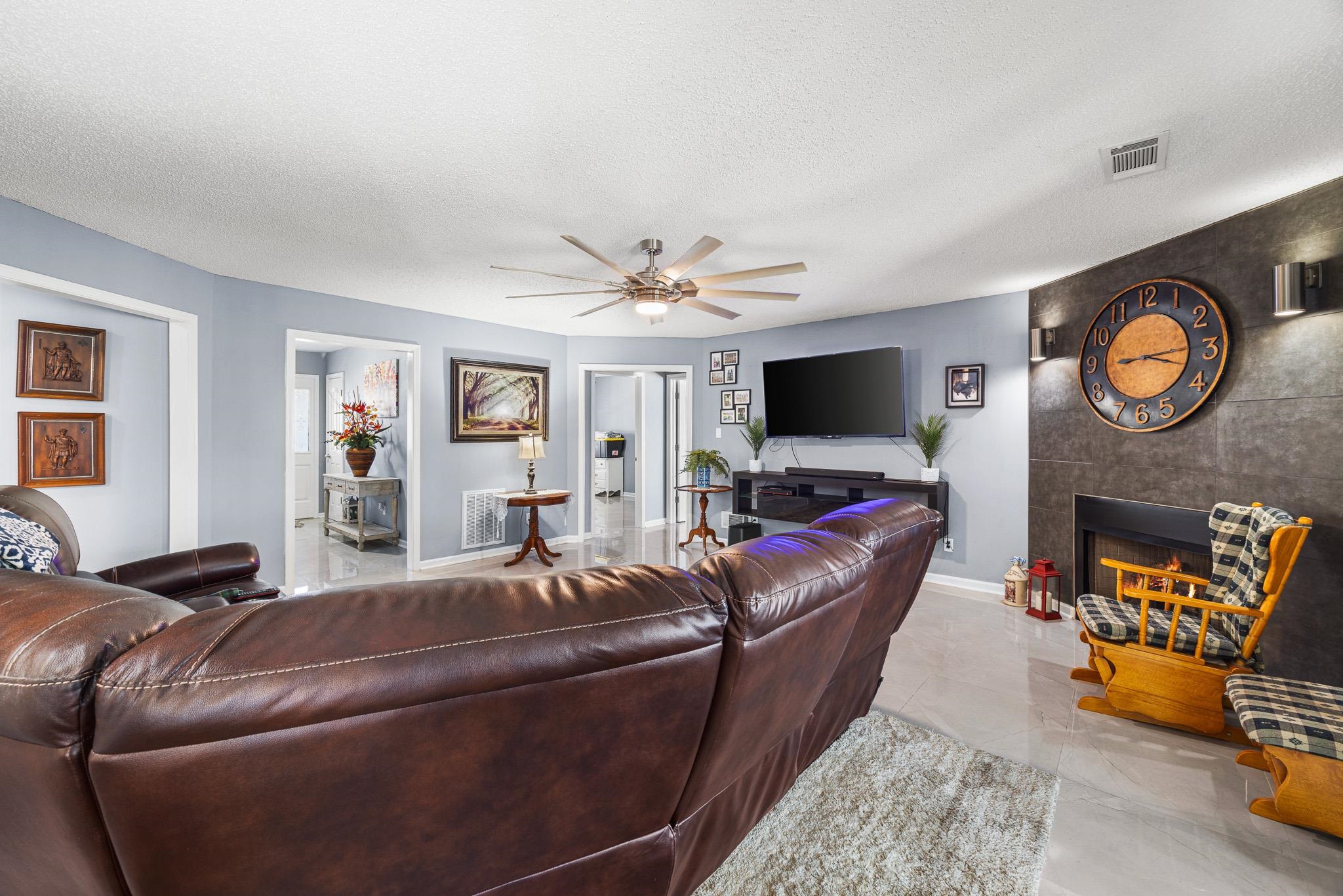149 Abby Road Drummonds, TN 38023 - Photo 8 of 38 Living room featuring ceiling fan, a fireplace, and a textured ceiling