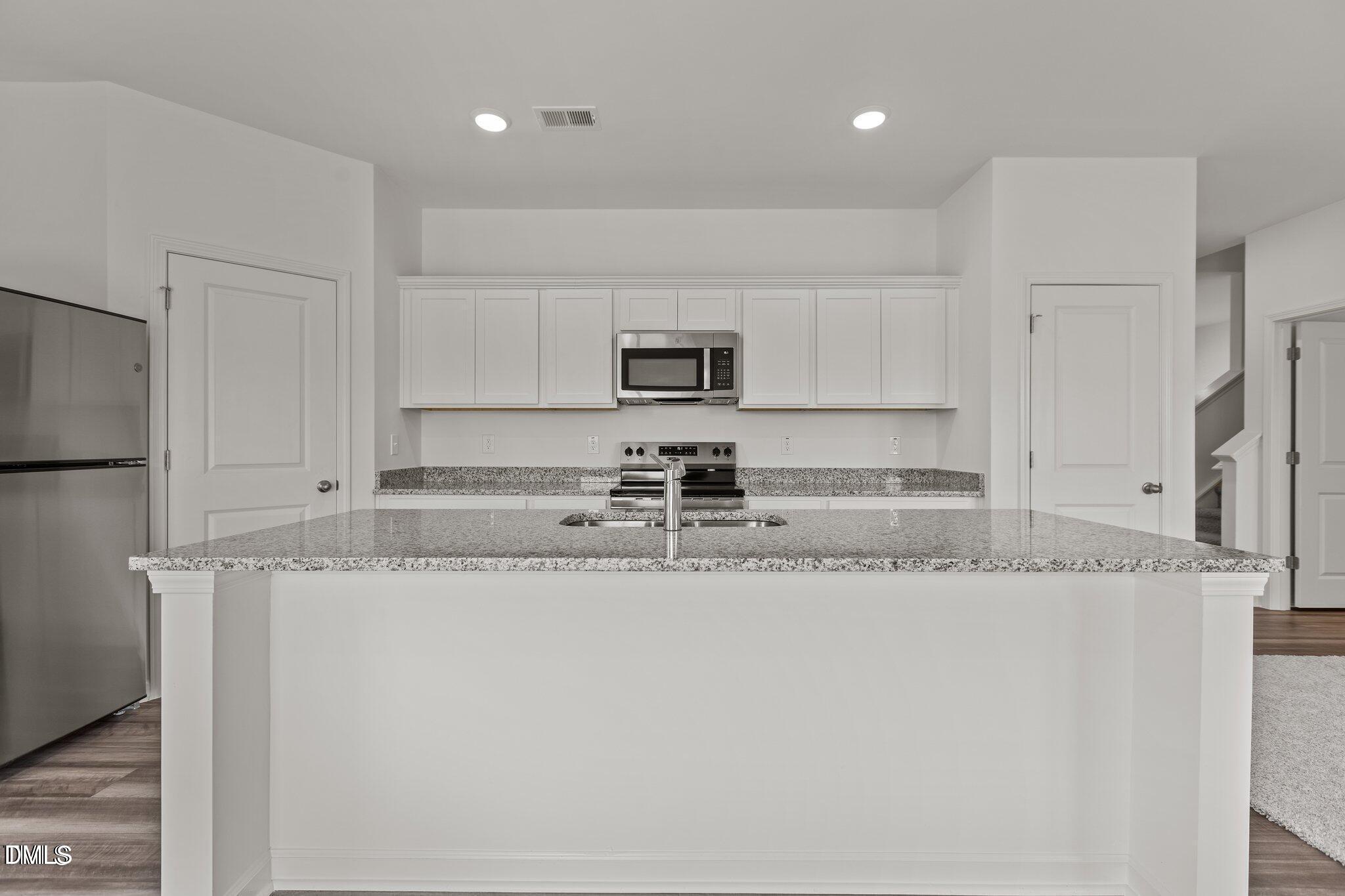 149 Bedstone Way Clayton, NC 27520 - Photo 2 of 22 a kitchen with granite countertop a sink a stove a microwave a refrigerator and white cabinets