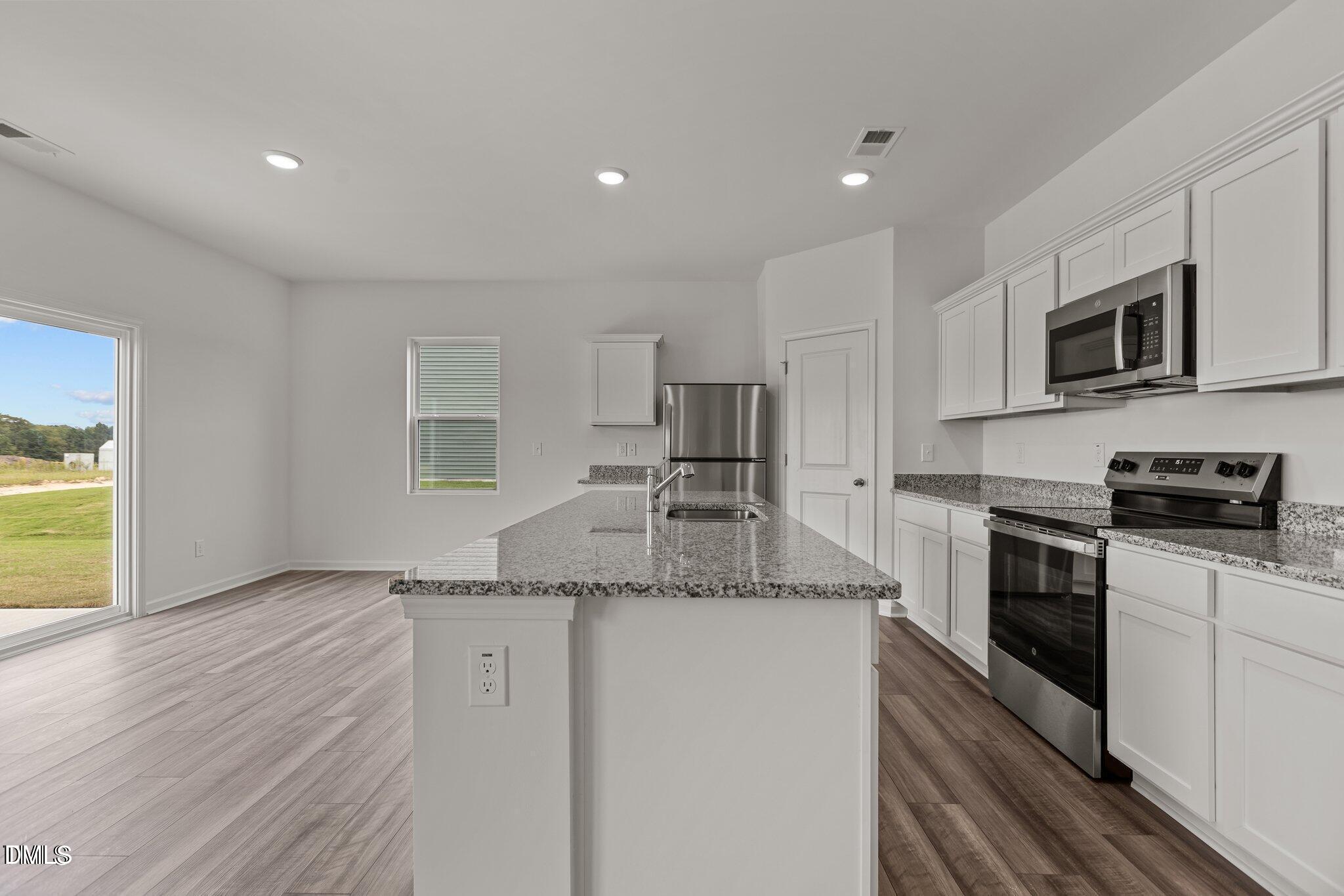 149 Bedstone Way Clayton, NC 27520 - Photo 3 of 22 a kitchen with stainless steel appliances granite countertop a stove a sink and a microwave