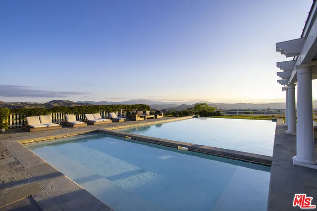a view of a swimming pool with a yard and furniture