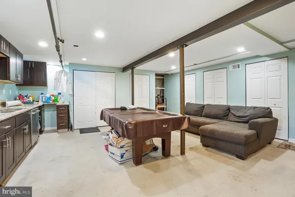 a living room with furniture a flat screen tv and a refrigerator
