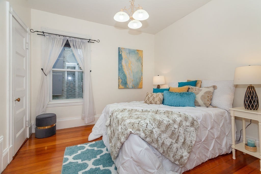 797 Columbia Road, Unit 3 Boston, MA 02125 - Photo 8 of 18 a bedroom with a bed and a chandelier