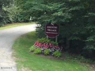 a sign that is sitting in the grass next to a road